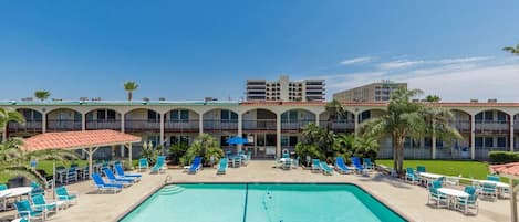A hotel with a swimming pool, multiple balconies, and outdoor seating areas.