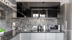 A modern kitchen with grey cabinets, a stainless steel refrigerator, a microwave, and a kettle. - Studio near Central Department Store (Minsk)