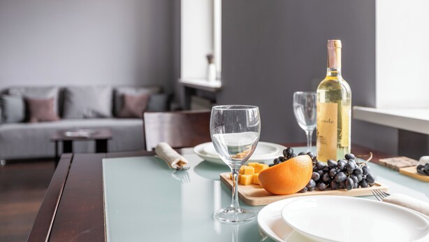 A dining table with a bottle of wine, glasses, cheese, grapes, and an orange. - Studio near Central Department Store (Minsk)