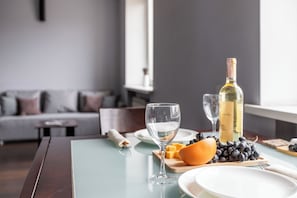 A dining table with a bottle of wine, glasses, cheese, grapes, and an orange. - Studio near Central Department Store (Minsk)