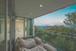 Ein moderner Balkon mit Blick auf einen Wald und das Meer.