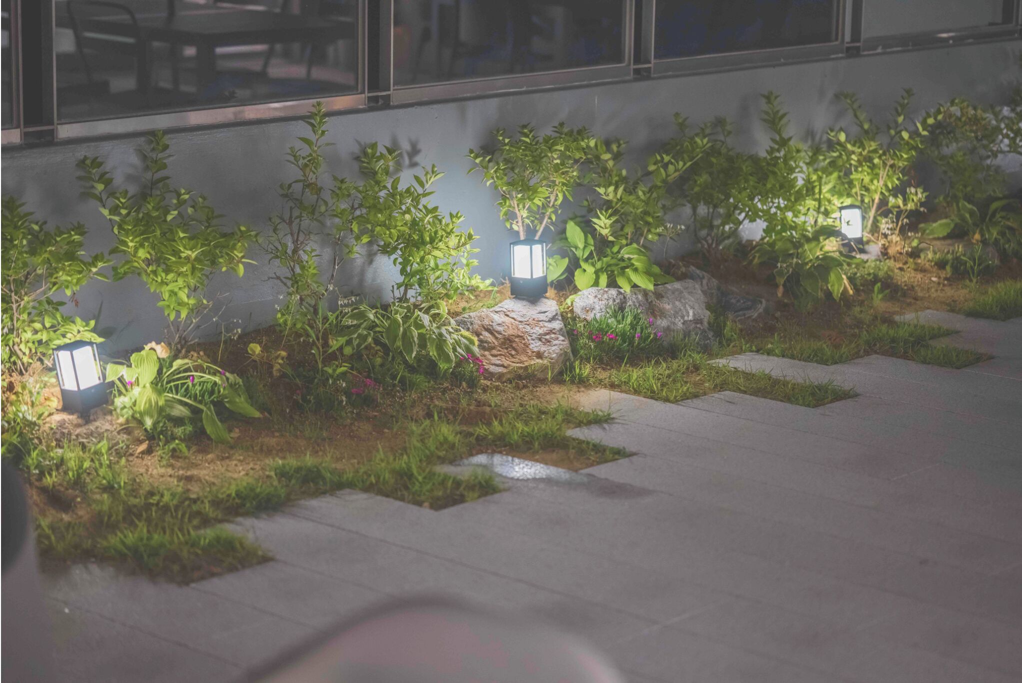 A landscaped outdoor area with potted plants and illuminated planters, likely part of a hotel or public space.