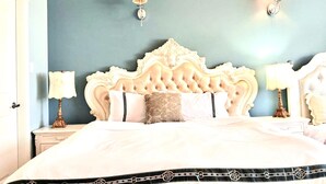 Una cama con cabecera capitonada, dos lámparas de noche y un cojín decorativo.