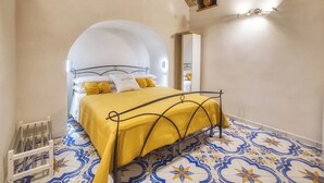 Un dormitorio con una cama, un arco blanco, un espejo y baldosas de suelo estampadas.