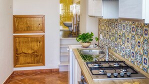 Una cocina con salpicadero de azulejos, estufa a gas y armarios de madera.