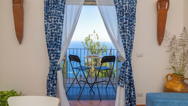 Un balcón con dos sillas, una mesa y vista al mar.