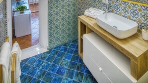 Un baño con lavabo, espejo y suelo de baldosas.