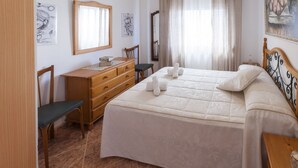 Ein ordentlich eingerichtetes Schlafzimmer mit Bett, Schminktisch, Stuhl und Nachttisch.