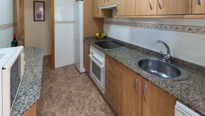 Eine Küche mit Granit-Arbeitsplatten, Holzschränken, einer Edelstahl-Spüle, einem eingebauten Ofen und einem Kühlschrank.
