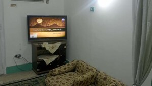 A living room with a sofa, a television, a ceiling fan, and a window with blinds. - Beautiful Apartment with 2 Bdr and 2 Living Rooms (Ard El lewa, El Mohandessin)