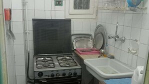A compact kitchen with a gas stove, an oven, a sink, and a fan on the wall. - Beautiful Apartment with 2 Bdr and 2 Living Rooms (Ard El lewa, El Mohandessin)