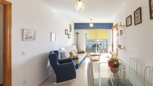 A living room with a sofa, armchairs, a glass dining table, and a view of the outside. - Apartment Nube in Grau i Platja (Gandia)