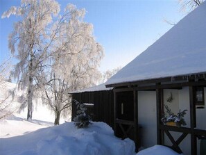 Un bâtiment enneigé, doté d’une façade en bois et d’un porche abrité.