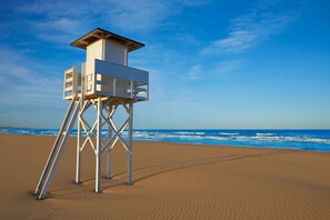 Ein Rettungsturm an einem sandigen Strand, im Hintergrund das Meer.