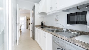 A modern kitchen with white cabinets, granite countertops, stainless steel appliances, and a built-in dishwasher. - Apartment Egeu in D nia (Denia)