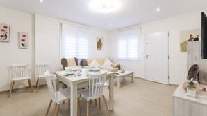 A bright, modern dining area with a white table set for four, surrounded by white chairs. - Apartment Egeu in D nia (Denia)