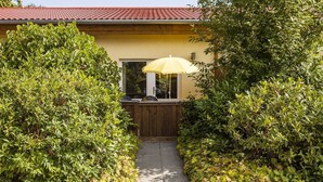 Un chemin menant à une maison à la façade jaune et au toit rouge.