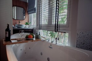 A modern bathroom with a large bathtub, a sink with a bowl, a mirror, a window with blinds, and a potted plant. - Au Lac Boutique Hotel (Ho Chi Minh City)