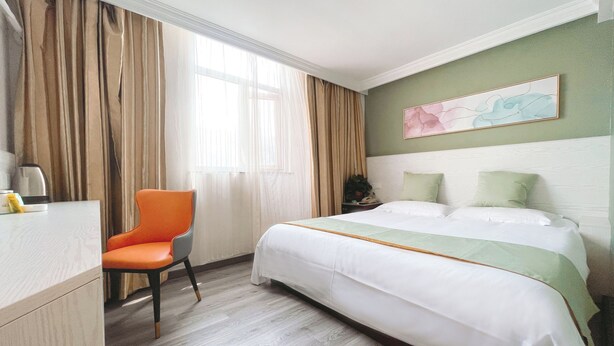A hotel room with a bed, a chair, a desk, and a window with curtains. - East Maples Inn Wanda (Wuxi)