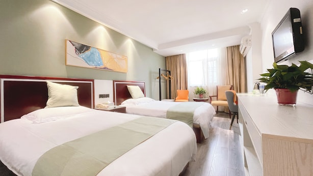 A hotel room with two beds, a desk, a chair, a television, and a painting on the wall. - East Maples Inn Wanda (Wuxi)