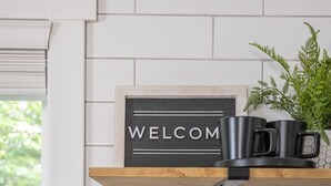 A kitchen with a 'WELCOME' sign, a coffee machine, and a stove. - Crow peak Cabin: Peaceful stay (Spearfish)