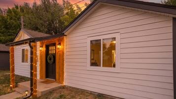 A single-story house with a porch, a door with a wreath, and string lights.