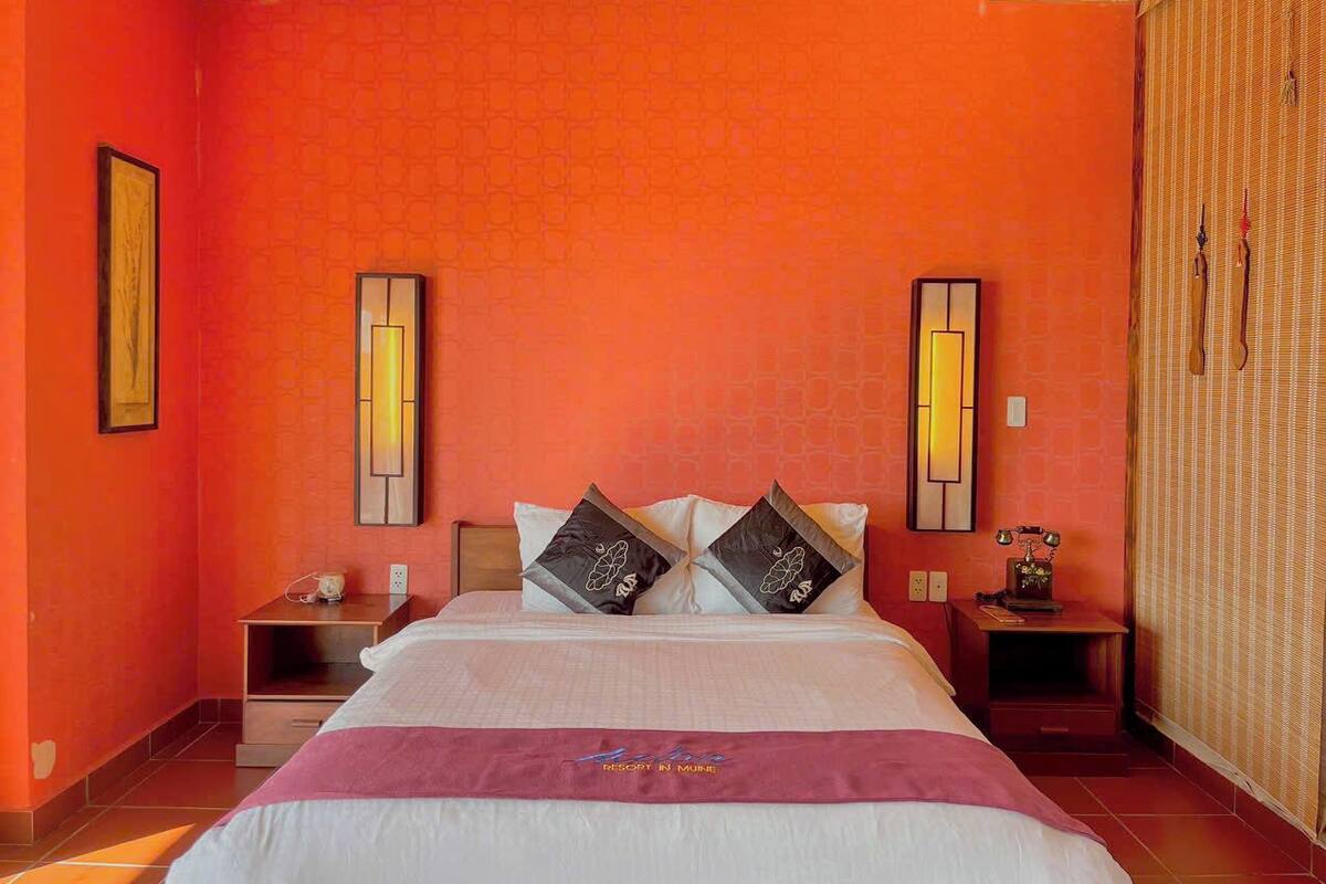 A hotel room with a large bed, two nightstands, and a wall-mounted lamp.