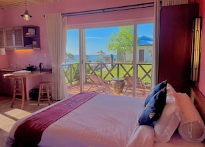 Une chambre avec un grand lit, un bureau et une vue sur la mer.