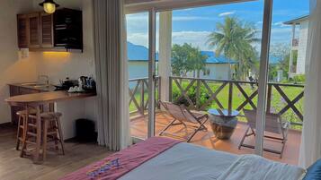 A room with a bed, a desk, and a balcony with chairs and a table.