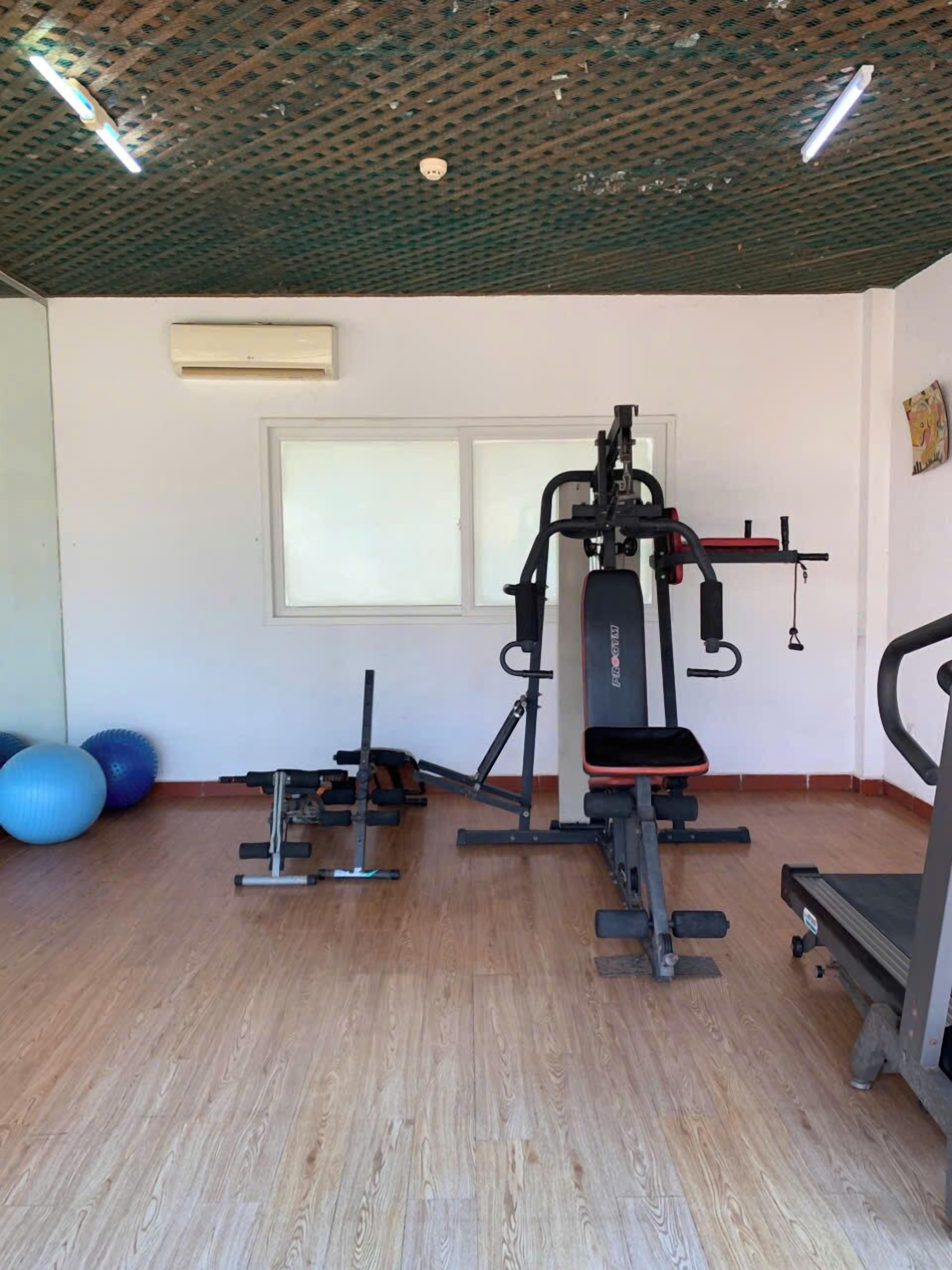 Une salle de sport équipée de matériel d’exercice, dotée d’un plancher en bois et d’une fenêtre.