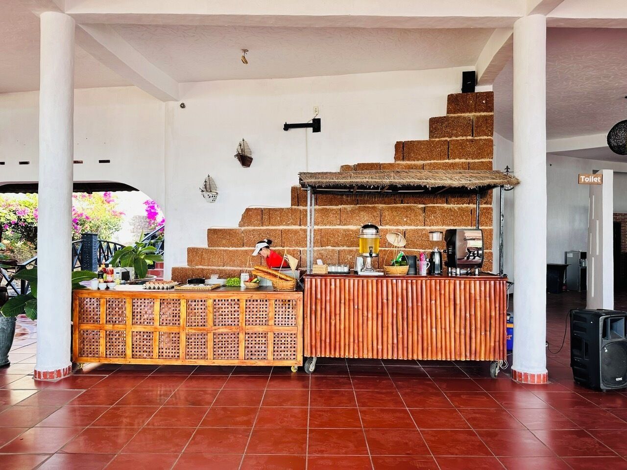 Un espacio al aire libre techado con un puesto de comida, una escalera y un letrero que indica un baño.