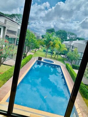 A rectangular swimming pool with a clear blue water surface, surrounded by a paved deck. - Prime Villa (Lusaka)