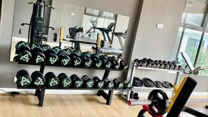 Une salle de sport équipée de matériel de musculation, d’un miroir et d’un porte-haltères.
