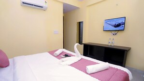 Une chambre d’hôtel équipée d’un lit, d’un téléviseur fixé au mur et d’un mini-bar.