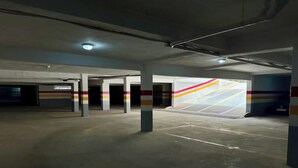 Un garaje de estacionamiento vacío con pilares de concreto y algunas puertas abiertas.