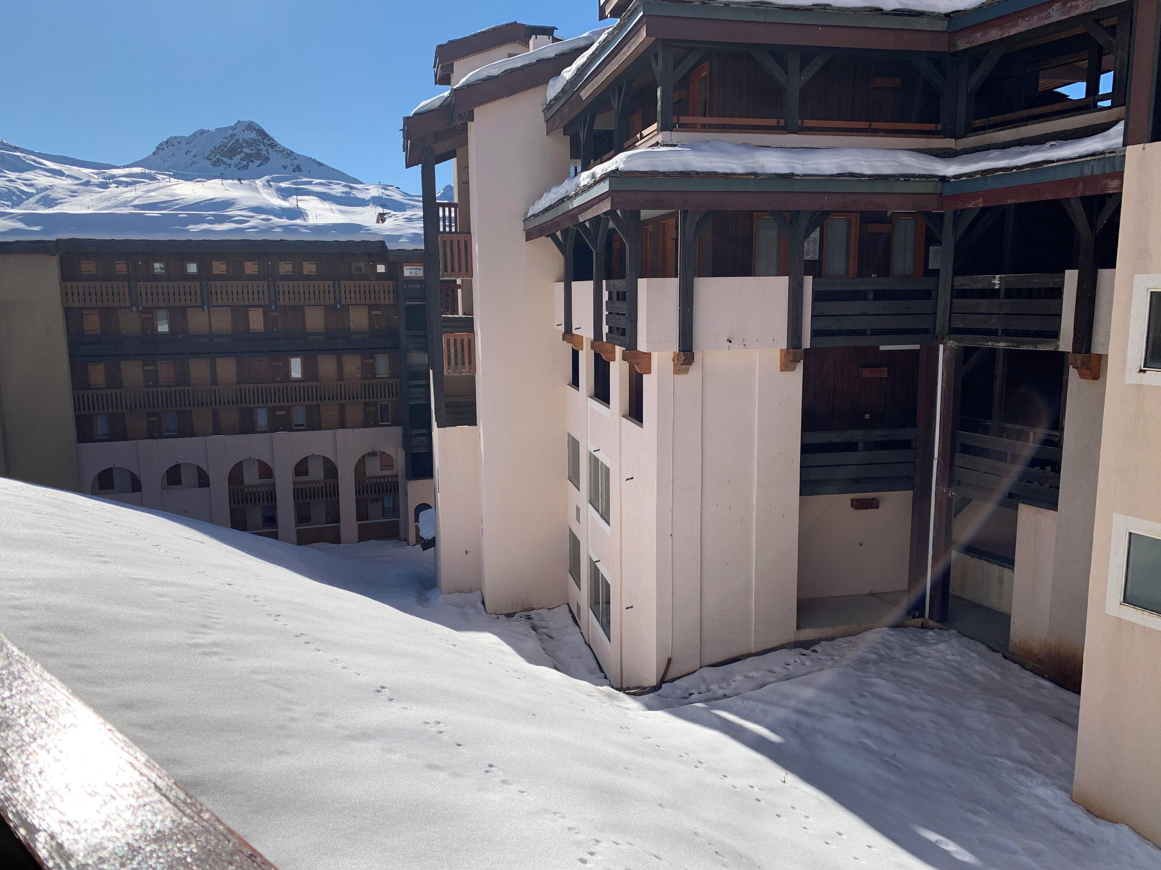 A snow-covered building with a balcony and a mountain in the background.