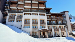 Ein mehrstöckiges Hotel mit Balkonen, einer Stein-Fassade und einer verschneiten Landschaft.