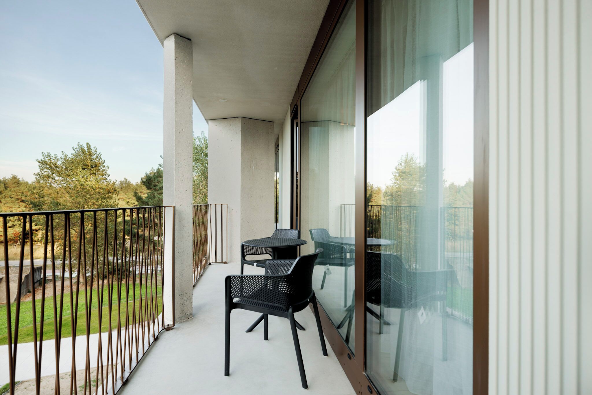 A balcony with a glass door, two tables, and chairs.