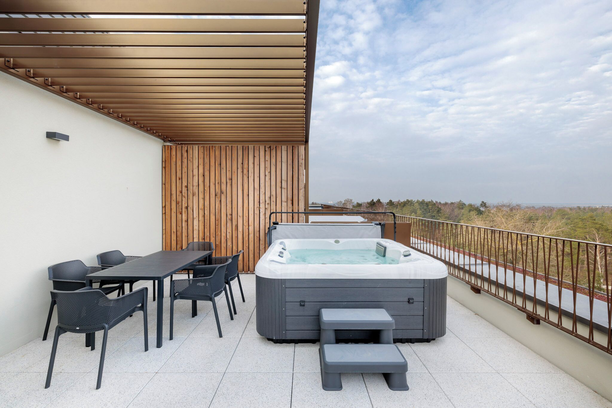 A balcony with a hot tub, a table, and chairs.