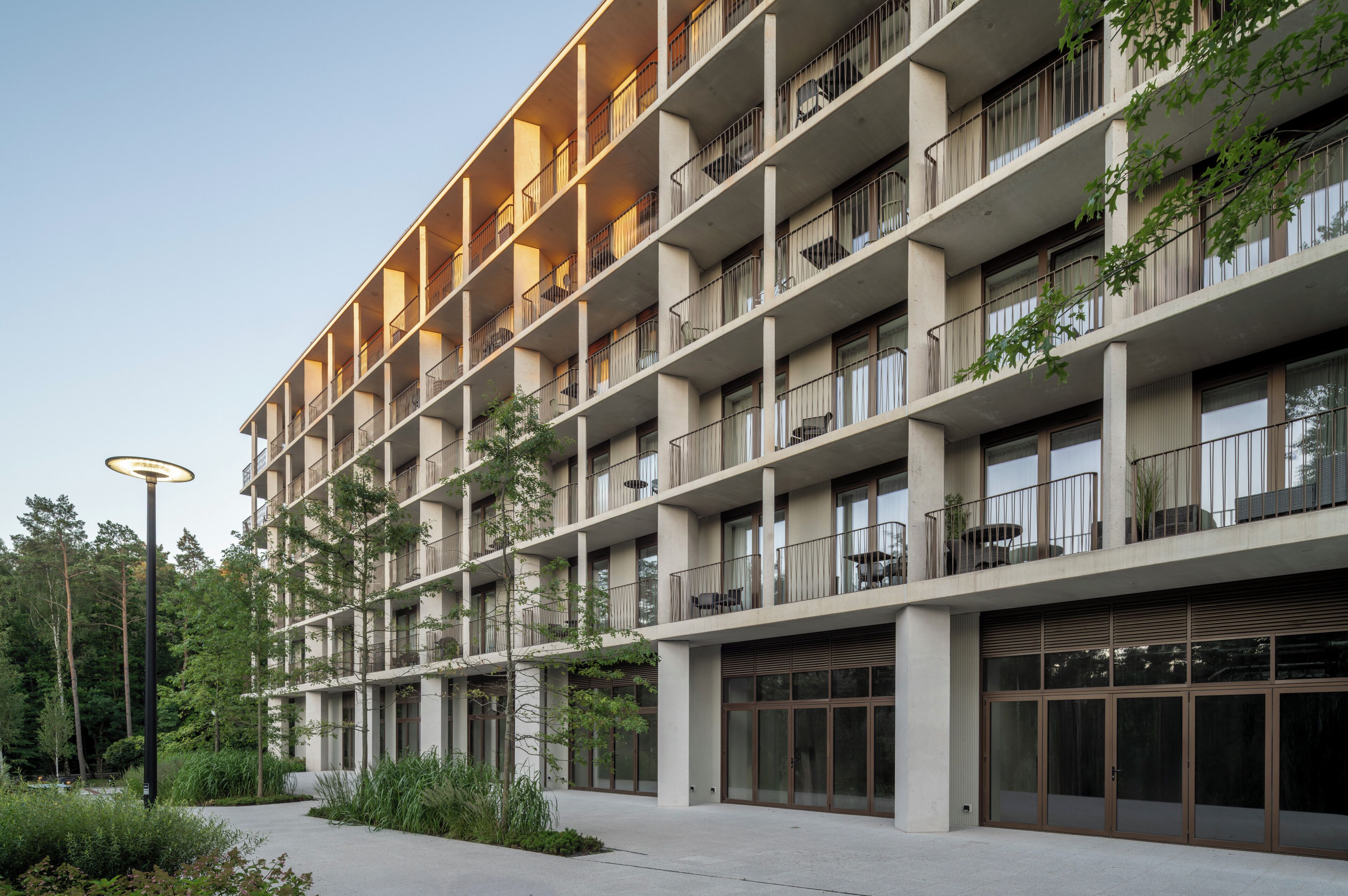 Un edificio de varios pisos con balcones, ventanas grandes y un camino pavimentado.