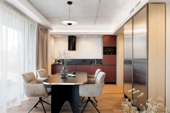 A modern kitchen with a central island, a dining area with four chairs, and a large window with sheer curtains. - Baltic Park Loft (Swinoujscie)