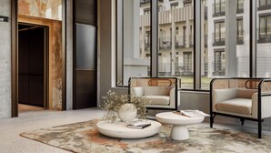Un interior moderno con un ventanal grande, dos sofás, una mesa de centro y un jarrón decorativo.