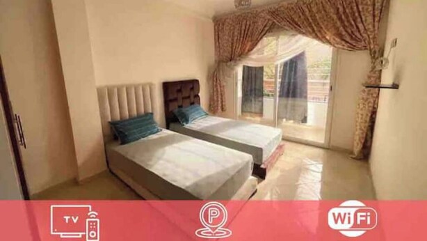 A bedroom with two beds, a TV, and a Wi-Fi symbol. - Spacious and comfortable Moroccan apartment (Temara)