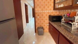 A compact kitchen with a refrigerator, microwave, and a dish rack. - Spacious and comfortable Moroccan apartment (Temara)