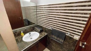 A bathroom with a marble sink, a towel rack, and a mirror. - Spacious and comfortable Moroccan apartment (Temara)