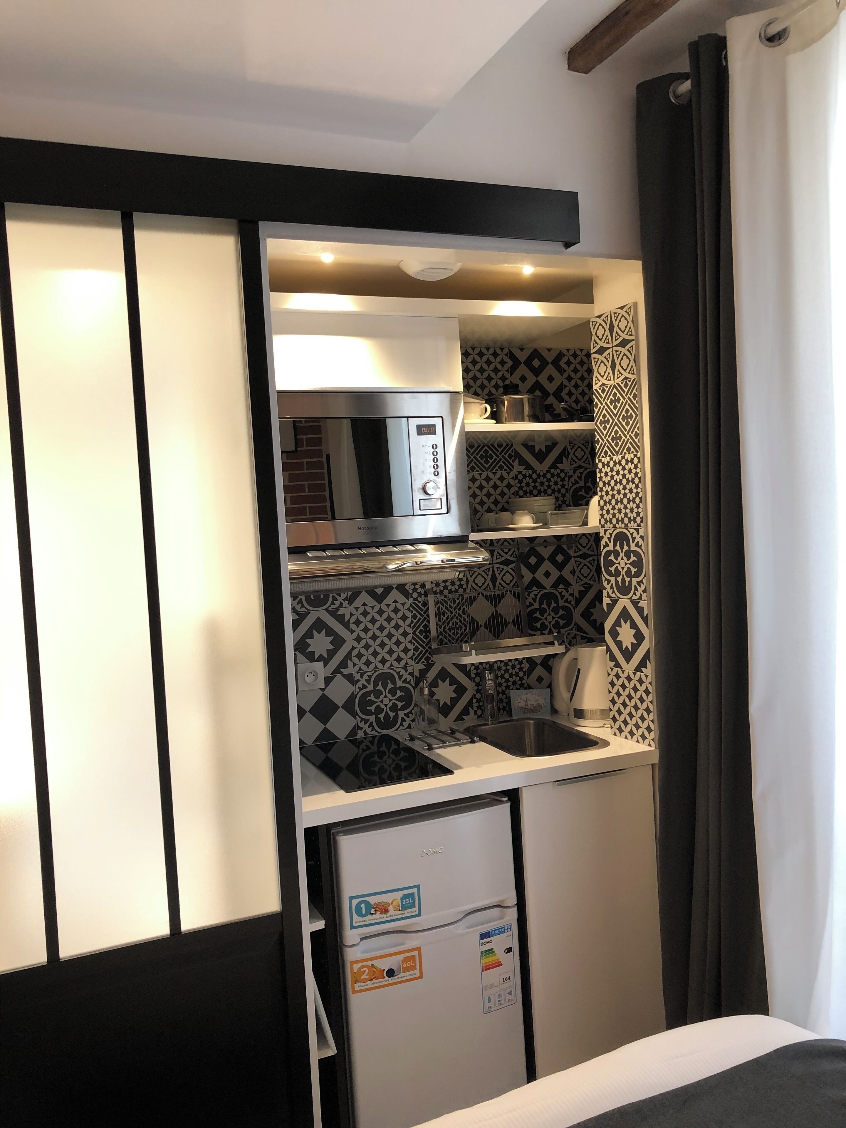 A compact kitchenette with a built-in microwave, a small sink, and a refrigerator.