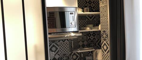A compact kitchenette with a built-in microwave, a small sink, and a refrigerator.