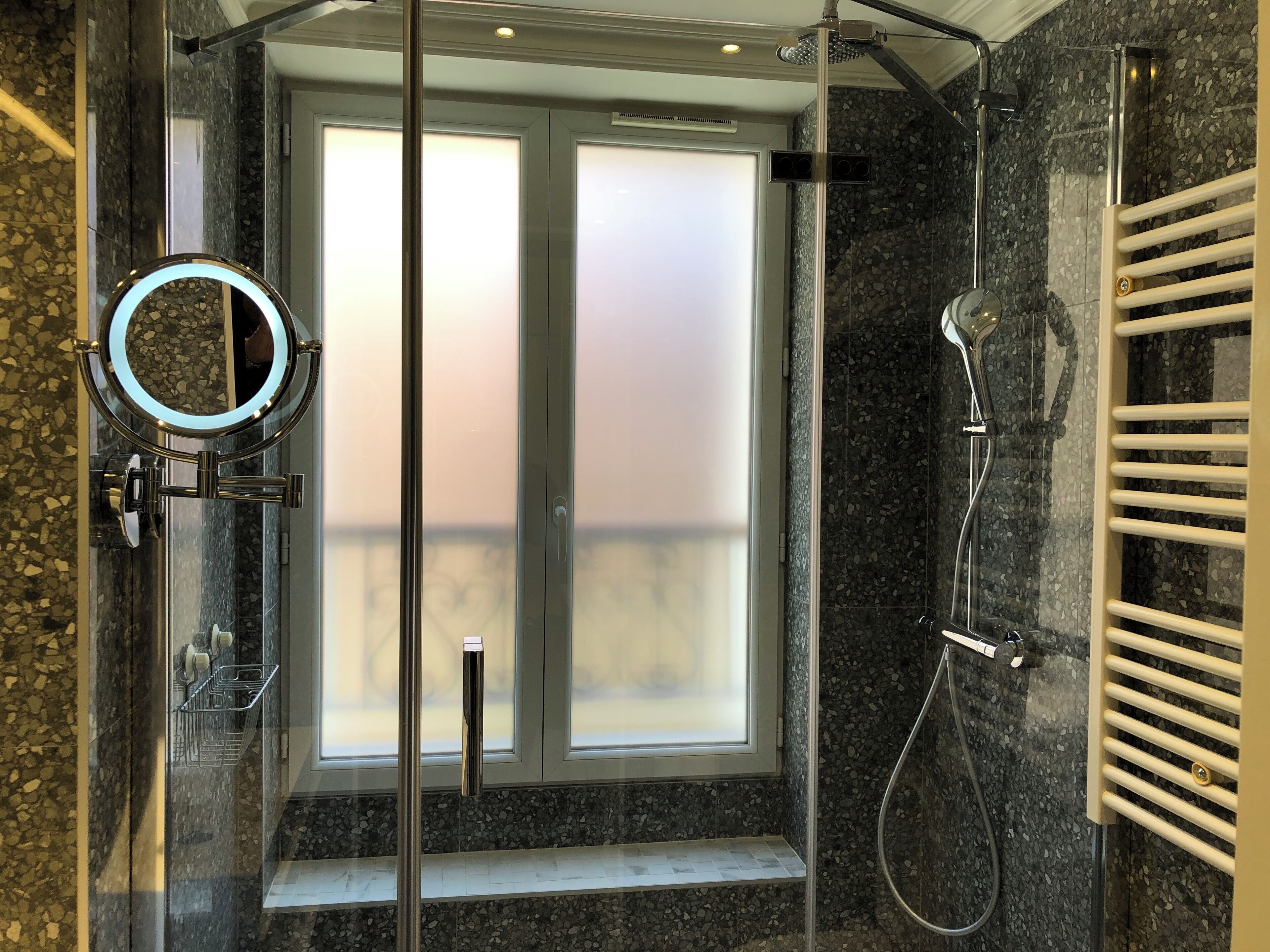 A modern bathroom with a glass shower enclosure, a built-in mirror, and a towel rack.