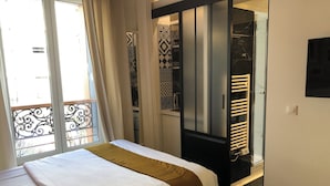 A bedroom with a bed, a wardrobe, a bathroom, and a balcony. - Résidence Labyrinthe (Paris)