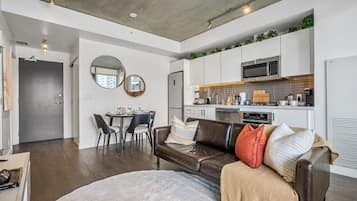 A modern apartment with a dining area, a living room with a sofa, and a kitchen.